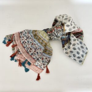 Lightweight cream scarf with a patchwork of floral prints, including a vine of blue and terracotta buds, a terracotta border, bands of mustard, sage green and navy, and a panel of small navy sprigs, finished with alternating teal and rust tassels.