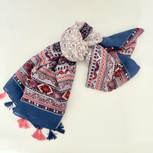 Lightweight scarf with wide solid blue ends, bands of geometric diamonds and zigzags in coral, pink, burgundy and navy, and a cream centre dotted with small diamonds, finished with alternating pink and navy tassels.
