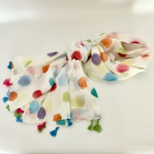 Sheer white scarf covered in soft, watercolour-style polka dots in red, orange, yellow, lime green, teal, sky blue, purple and pink, finished with tassels in fuchsia, blue and green.