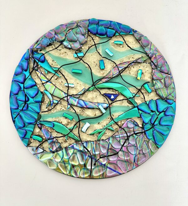 A circular glass piece with beautiful blue and green designs.