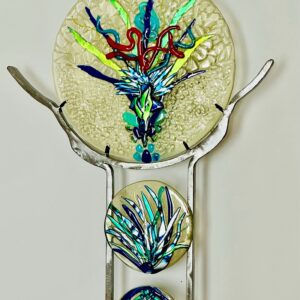 A metal stand with a glass plate on it, showcasing a sparkling feathers triptych