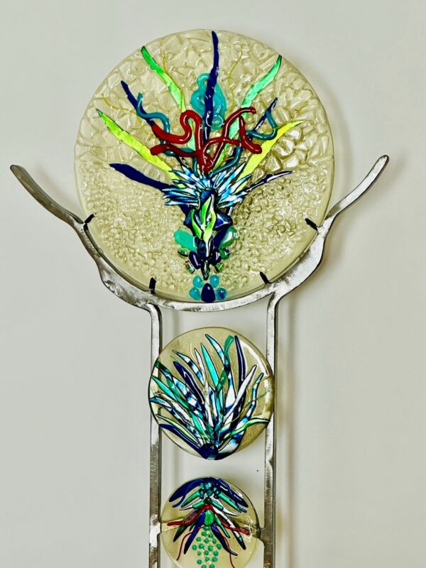 A metal stand with a glass plate on it, showcasing a sparkling feathers triptych